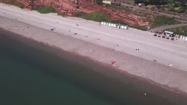 Vliegen Een Groene Zee Langs Een Kiezelstrand Met Kleurrijke Hutten — Stockvideo