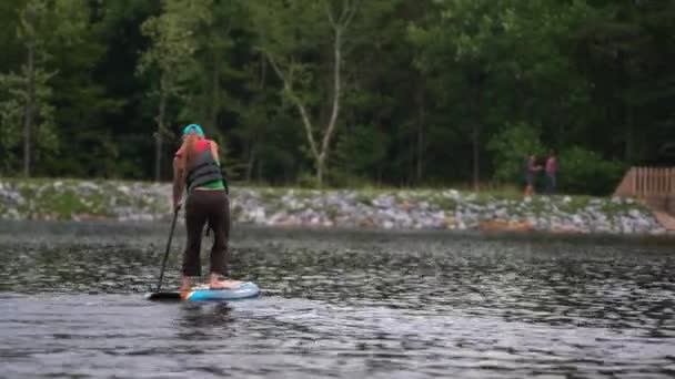 山の湖のカメラから出て行くパドルボード上の熟女 — ストック動画