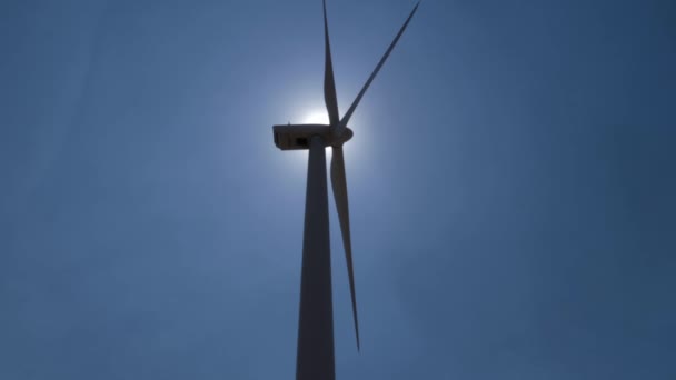 風車発電機は太陽の光でシルエットながら減速しながら回転します — ストック動画