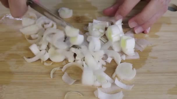 キッチンカウンターで料理をしている人 彼は玉ねぎと野菜をナイフで切ってる — ストック動画
