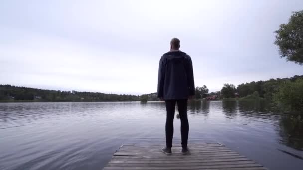 Модный Молодой Человек Стоящий Пирсе Наслаждающийся Видом Спокойное Озеро Швеции — стоковое видео