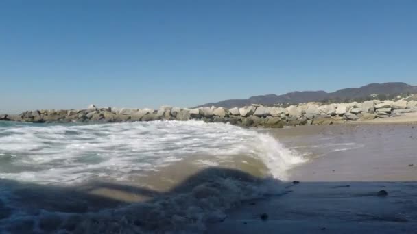 Κύματα Κυματίζουν Στην Ακτή Δίπλα Μια Προβλήτα Βράχου Μια Ηλιόλουστη — Αρχείο Βίντεο