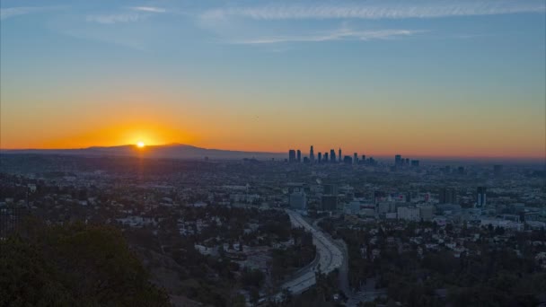 朝の交通量が多いロサンゼルスの街並みに劇的なオレンジ色の日の出の時間経過 — ストック動画