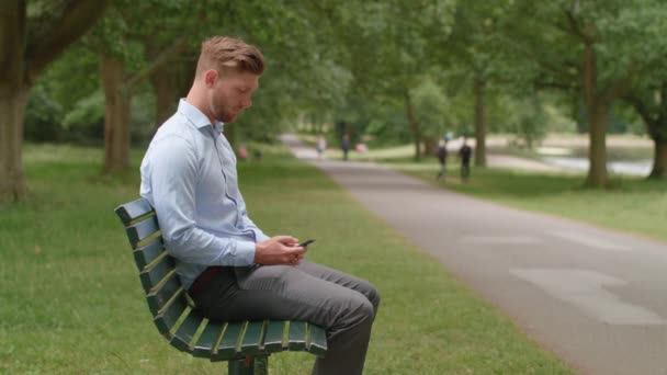 Vonzó Férfi Ült Padon Parkban Fogadja Telefonhívást Egy Barátjától — Stock videók