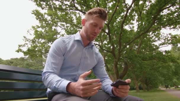 Hombre Sentado Banco Parque Viendo Deportes Partido Teléfono Cámara Lenta — Vídeo de stock