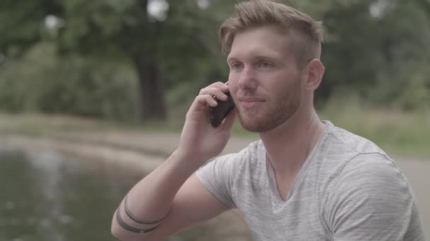 親しい友人からの電話を受ける池のそばの男 採点なし — ストック動画