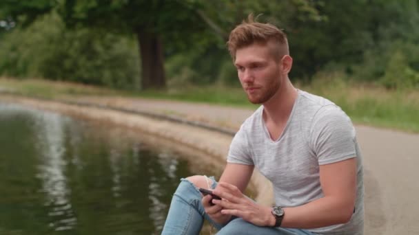 Göl Kenarında Oturan Adam Arkadaşından Telefon Alıyor — Stok video