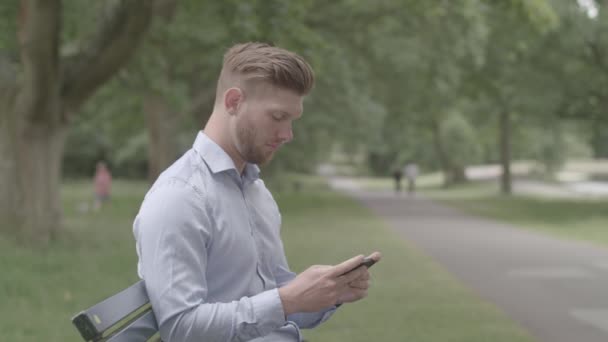 Man Sat Bench Park Oglądanie Meczu Sportowego Telefonie Ungraded — Wideo stockowe