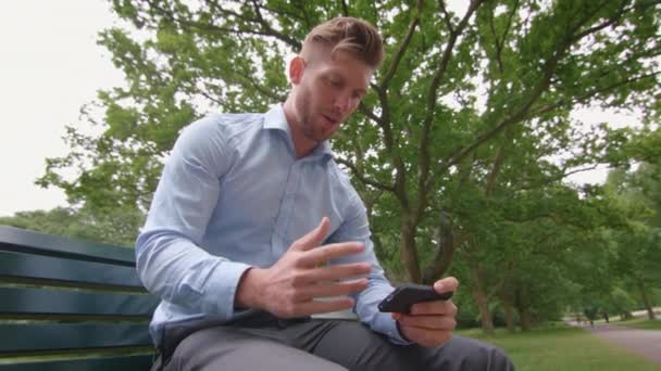 Man Sat Bench Park Watching Sports Match His Phone Slow — Stock Video