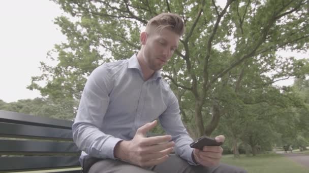 Man Satt Bänk Park Titta Sport Match Sin Telefon Långsam — Stockvideo