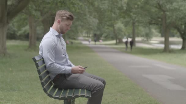 Atrakcyjny Mężczyzna Siedzi Ławce Parku Odbiera Telefon Znajomego Niesklasyfikowane — Wideo stockowe