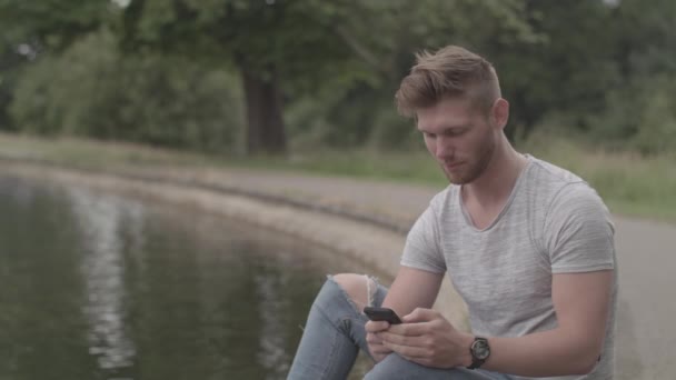 Hombre Sentó Usando Teléfono Inteligente Junto Lago — Vídeo de stock