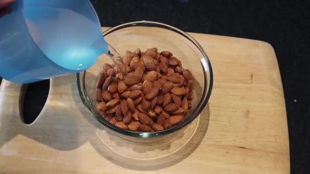 Pouring water onto almonds in a bowl of water to be later turned into almond milk