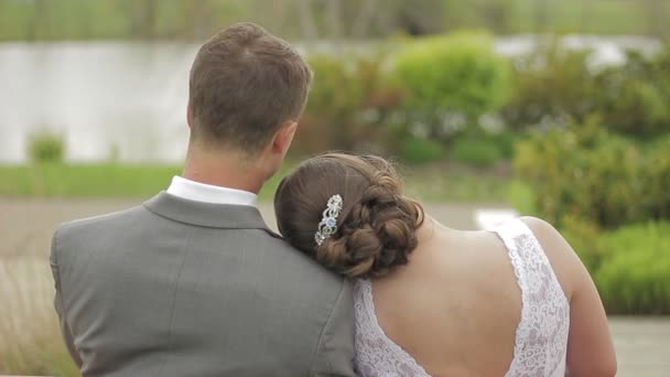 このクリップには 結婚後すぐに公園のベンチで夫の肩の上に頭を休める妻が含まれています 彼はそれから横になって彼女にキス — ストック動画