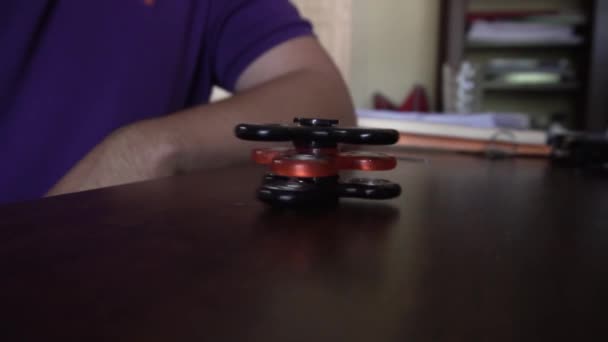 Man Zit Kijkt Drie Fidget Spinners Draaien Top Van Elkaar — Stockvideo