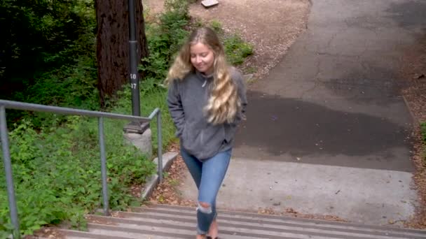 A college girl walking up a flight of stairs on campus.