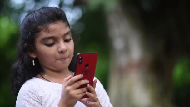 Een Gelukkig Klein Aziatisch Meisje Speelt Met Haar Mobiele Telefoon — Stockvideo