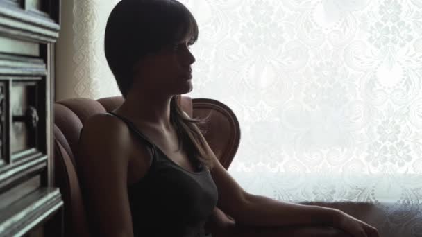 Силуэт Молодой Женщины Сидящей Кресле Окном Думая — стоковое видео