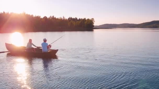 Gyönyörű filmes felvétel egy férfiról, aki egy evezős hajóról horgászik naplementekor.