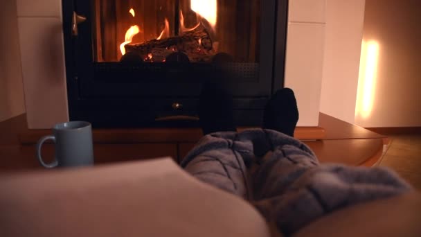 autumnal and winter background of a cozy person reading a book in front of a comfortable fireplace with a cup of hot coffee or chocolate, while the fire is crackling