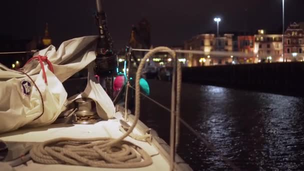 背景に都市の照明がぼやけている夜に白い帆船にロープと光沢のあるアンカーの詳細ショット — ストック動画