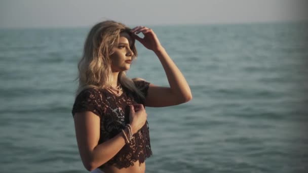 Blond Flicka Justerar Håret Stranden Medan Solen Skiner Hennes Ansikte — Stockvideo