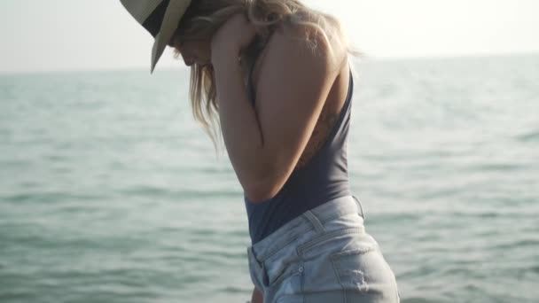 Ein Blondes Mädchen Fedora Blickt Bei Sonnenuntergang Ins Wasser — Stockvideo