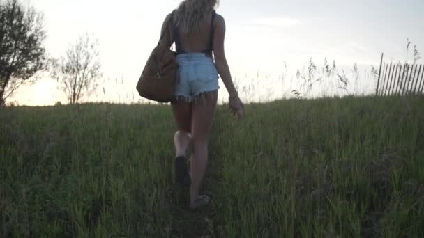 Blonde Girl Playfully Looks Her Shoulder She Walks Grassy Hill — Stock Video