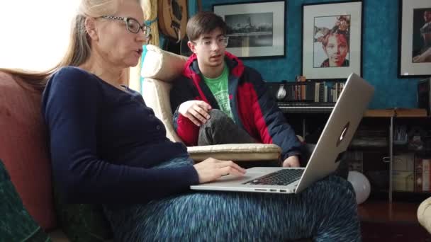 Szekrény érett anya laptop az ölében, míg a tini fiú eléri, és beszél.