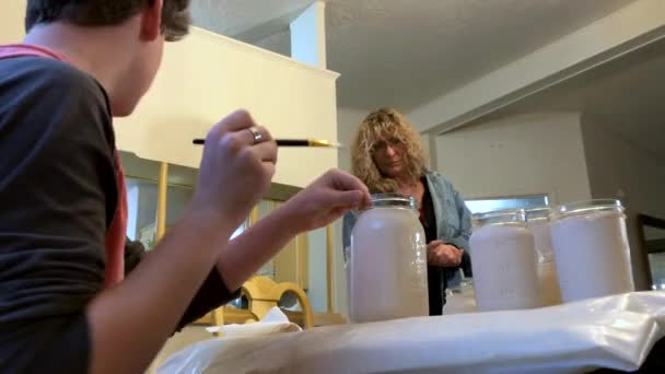 Adolescent Garçon Peinture Maçon Pots Tandis Que Âgé Femelle Assied — Video