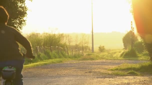 自転車に乗るのは初めて田舎の日没の美しい光の中で — ストック動画