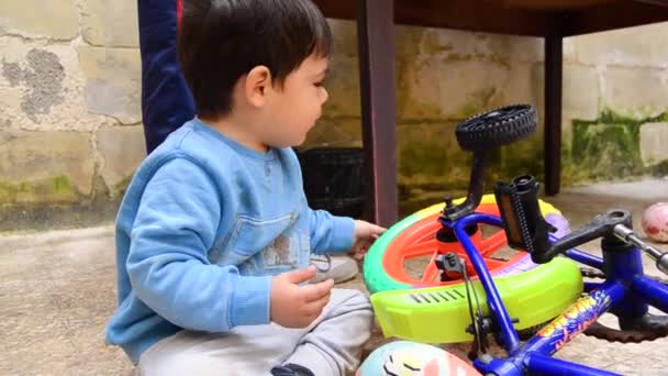 可爱有趣的学步的男孩儿在玩他的自行车支撑物的轮子 — 图库视频影像