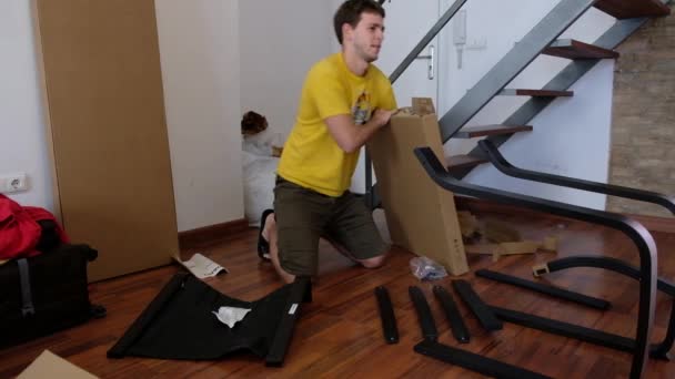 若い男は段ボール箱からアンパック家具の作品を展開しています — ストック動画