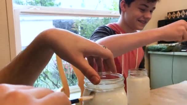 Teenage Boy Smiling While Painting Mason Jars Home His Brother — ストック動画