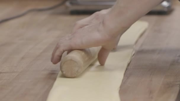 Handmade pasta is being rolled in slow motion with a pasta maker in the background