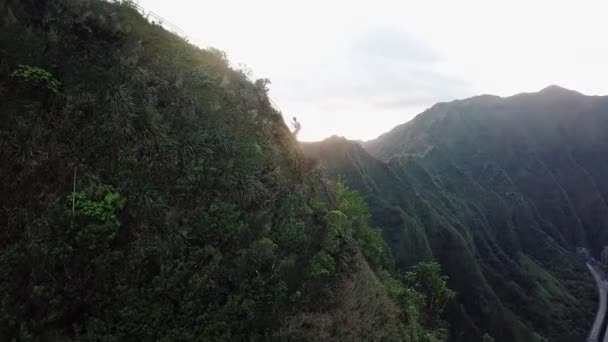 ハワイ 米国の晴れた夏の夜に 日没時に ハワイの山の頂上に向かって階段を登る人の空中 ドローンショット — ストック動画