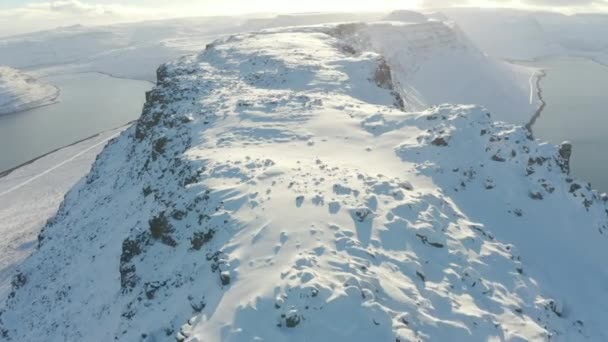 AERIAL BIRDSEYE TILT LE: Kövesse végig csúcsa / gerince izlandi hegyvonulat, mély hó recés sziklák gyönyörű naplemente. közel Isafjordur, Westfjords, Izland, Európa