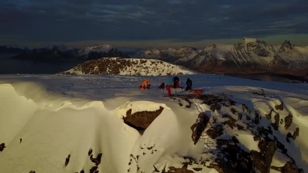 雪の山の頂上でスキーヤーギアをチェックして梱包します 午後遅くに海が見えます 彼らの方へ太陽が北へ移動します — ストック動画