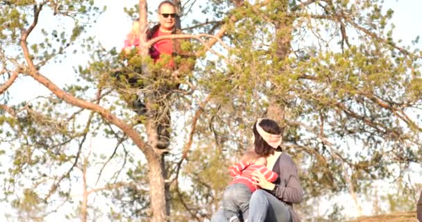 小さな山の上でピクニック休憩を持っているマルチ世代の家族 女の子と祖父は木の上に座って 静的スローモーション — ストック動画
