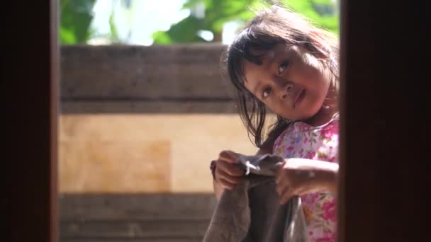 Doce Menina Indonésia Sorri Através Uma Janela Enquanto Limpa Criança — Vídeo de Stock