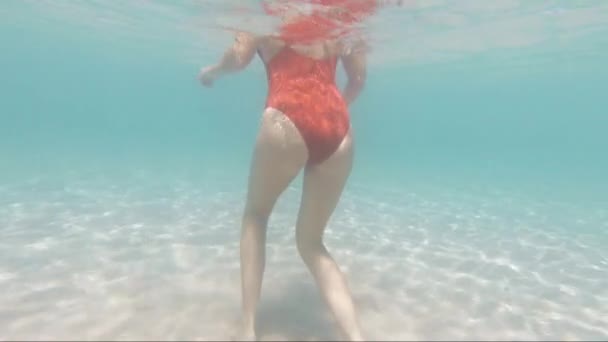 从水下到水面的慢镜头展现了一位年轻漂亮的女子坐在菲律宾北部纳卡潘海滩清澈的海水中 这是一个完美的度假和梦想的目的地 — 图库视频影像
