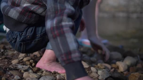 Ein Kleiner Junge Hebt Einen Felsen Ufer Eines Flusses Auf — Stockvideo