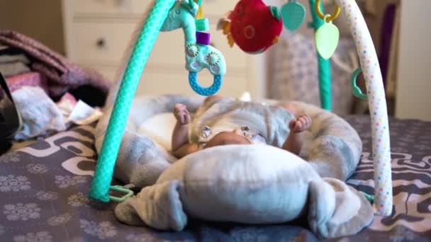 Очаровательная Новорожденная Девочка Двигает Ногами Руками Колыбели Глядя Красочные Игрушки — стоковое видео