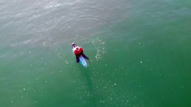 在加利福尼亚州亨廷顿海滩 一名穿着红色湿衣的冲浪运动员 Zander Adelsohn 在4千架无人驾驶飞机在太平洋上空盘旋升起 等待海浪的到来 — 图库视频影像