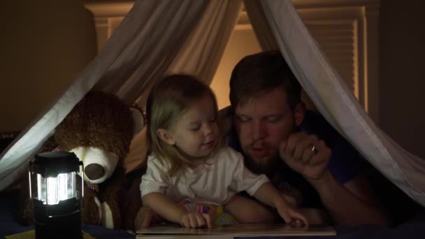 爸爸在睡觉的时候在毛毯堡垒给小女儿读书 — 图库视频影像