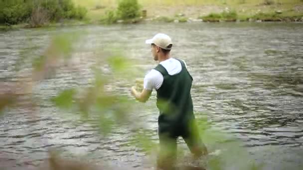 フライフィッシング中にフックを投げる白人の男性漁師のショット ユタ州のプロボ川の真ん中に立っている — ストック動画