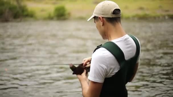拍了一个男渔夫穿着雨衣在飞鱼时 他在准备钓饵 然后飞了起来 他站在犹他州普罗沃河的中间 — 图库视频影像