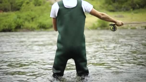 一名白人男性渔夫在飞鱼捕鱼时抛出鱼钩 动作缓慢 他站在犹他州普罗沃河的中间 — 图库视频影像