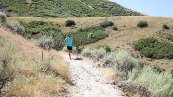 スローモーションユタ州ドレイパーシティの屋外山岳トレイルを走るアクティブな男のショット 背後にはワサッチ山脈が見える — ストック動画