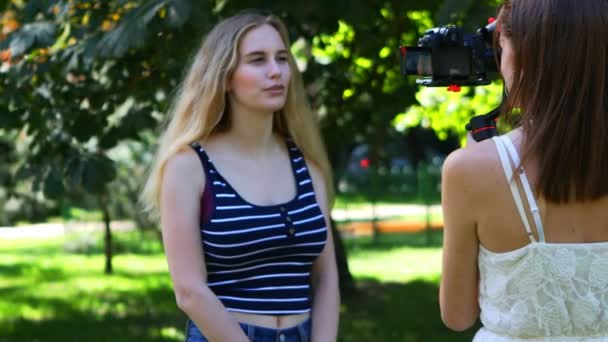 Két fiatal nő időeltolódása, akik egy szabadtéri interjút készítenek fényképezőgéppel és gimbal felszereléssel
